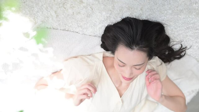 Beautiful adult woman lying on her back and closing her eyes Vertical video of napping and sleeping image with green foreground blur