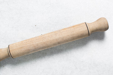 Top view of wood rolling pin on a white granite countertop, overhead view of a wooden rolling pin