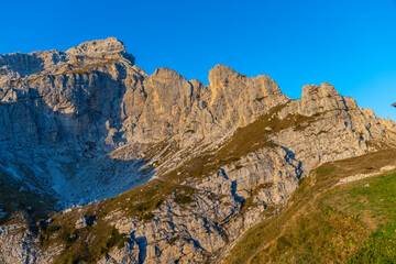 Sunset in the mountains. Red and orange burning sky horizon behind the alpine mountain range. Rocky mountain peaks of the Dolomites at sunset and dawn at sunrise light sunrays going through the clouds