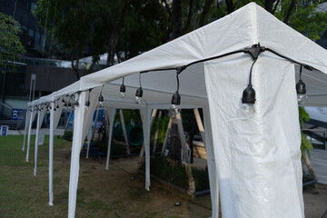 White teepee tent pitched on green grass under a vast blue sky, perfect for a summer camping...