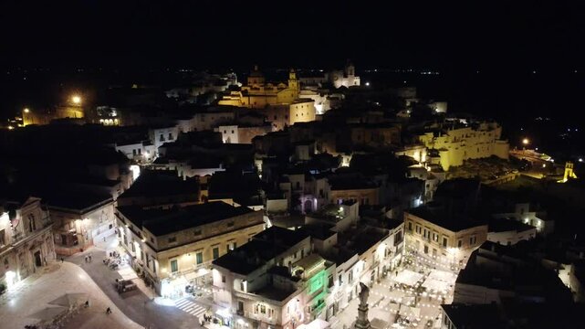 V&iacute;deo em vis&atilde;o a&eacute;rea noturna de Ostuni, It&aacute;lia, capturando a beleza da cidade iluminada com suas ruas estreitas e arquitetura hist&oacute;rica, destacando o charme mediterr&acirc;neo e a tranquilidade noturno