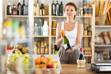 Adult saleswoman offers to buy bottle of wine in grocery store