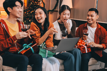 Group of young Asian man and women as friends having fun at a New Year's celebration, holding gift boxes standing by Christmas tree decoration, midnight countdown Party at home with holiday season.