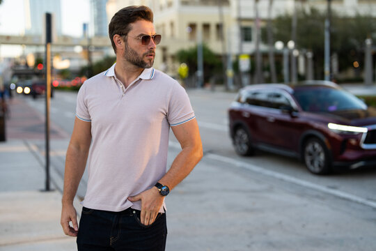 Stylish man wearing sunglasses and shirt. Handsome man outdoors portrait. Portrait of stylish male model outdoor. Fashion male posing near skyscraper on the street. Fashionable man in urban style.
