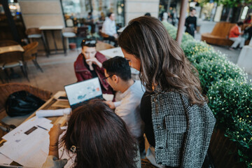 A diverse group of business people discuss ideas and analyze concepts while working together at an outdoor cafe. The scene captures teamwork and collaboration in a casual setting.