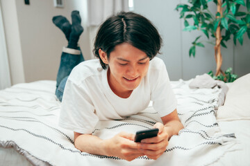 ベッドでスマホを見る男性
