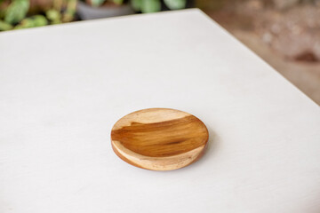 Round wooden coasters on white table with blurred ornamental plants background