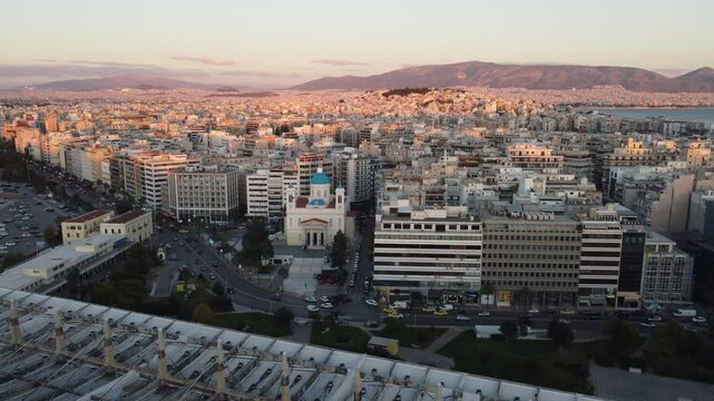 Vis&atilde;o a&eacute;rea do centro urbano de Atenas ao fim do dia, capturando a beleza da cidade iluminada, com o Parthenon ao fundo e as luzes urbanas come&ccedil;ando a brilhar