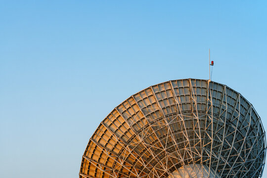 Radio telescope giant paraboloid surface in morning sunlight with blue sky background