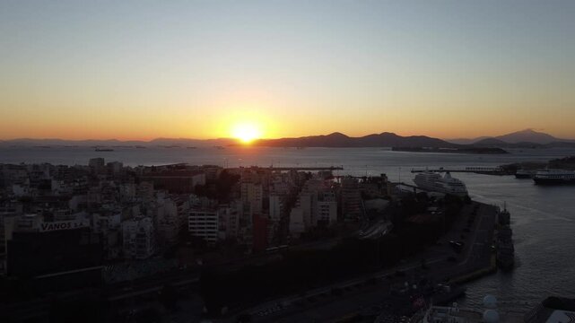 Fim de tarde em Atenas, Gr&eacute;cia, com o p&ocirc;r do sol iluminando o centro urbano. Cen&aacute;rio deslumbrante com a Acr&oacute;pole ao fundo e a cidade banhada por tons dourados e laranja