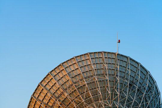 Radio telescope giant paraboloid surface in morning sunlight with blue sky background