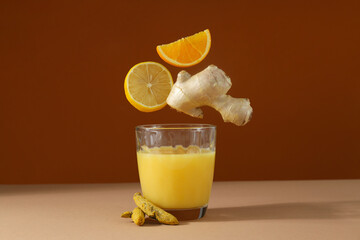 Glass with juice and falling ingredients on dark red background