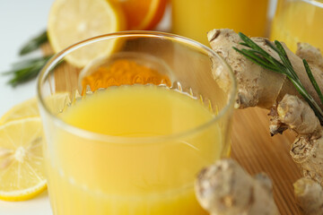 Glass with juice, wooden board and ingredients on white background, close up