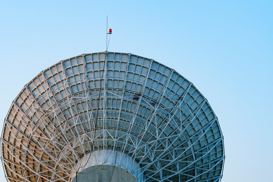 Radio telescope giant paraboloid surface in morning sunlight with blue sky background