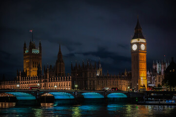 Big Ben and the Houses of Parliament illuminated at night, viewed from the Thames River, iconic...