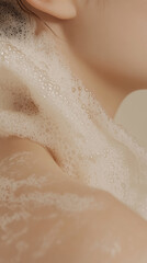 Inviting close up of woman shoulder and neck with creamy soap forming rich, soft bubbles enhancing her radiant skin tone