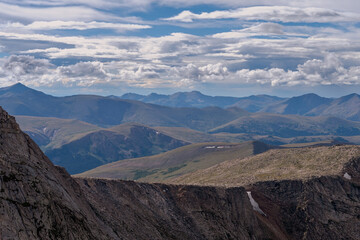 Expansive mountain landscape under a cloudy sky showcases rugged terrain and rolling hills in a remote wilderness area during daylight hours