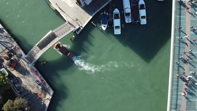 V&iacute;deo a&eacute;reo de um barco vermelho navegando pelos canais de Veneza, It&aacute;lia, destacando a beleza das &aacute;guas, as pontes hist&oacute;ricas e o charme &uacute;nico da cidade dos canais