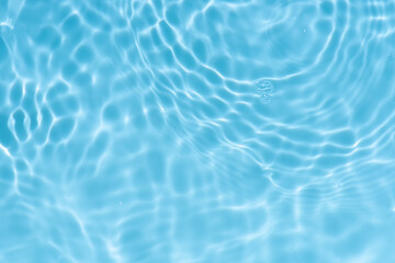 Blue water with ripples on the surface. Defocus blurred transparent blue colored clear calm water surface texture with splashes and bubbles. Water waves with shining pattern texture background.