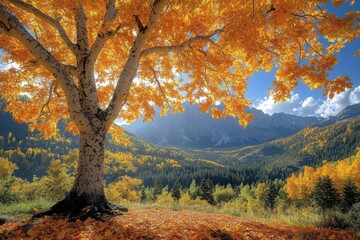 Fototapeta premium A large autumn tree with golden leaves standing in a picturesque landscape against a mountain backdrop, creating a vibrant and seasonal nature scene perfect for fall-themed designs.