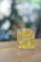 Cool honey lemon in a clear glass with lemon slice on wood table