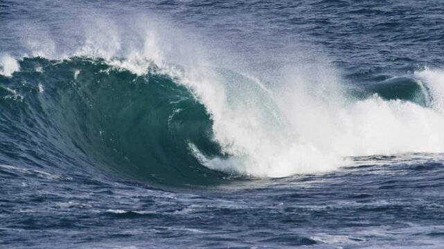 slow motion wave curls into a barrel, foam ball spraying out from the deep hollow