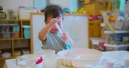 young child holding a syringe while engaging in imaginative play doing chemistry experiments science, explores and learns through play with educational toys environment. - Powered by Adobe