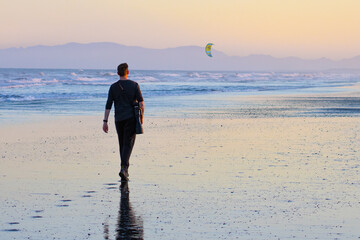 A man photographer walks on stunning vast, long Waikuku Beach next to Ashley river with impressive...