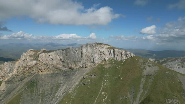 Rugged Korab Mountain peak under a blue sky with scattered clouds in Albania, aerial view