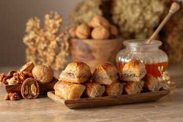 Baklava with walnuts and honey on a beige background.