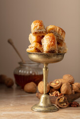 Baklava with walnuts and honey on a beige background.
