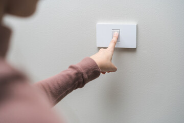 Asian young woman hand turn off on lighting switch at home room. Finger pushing light switch turn...