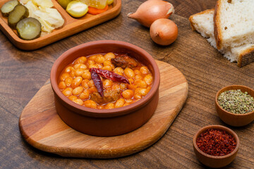 Baked Bean Dish in a Clay Pot. Served with pickles and onions. A traditional Turkish cuisine dish.
