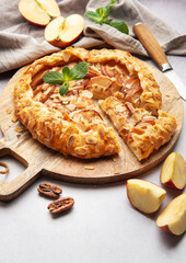Delicious homemade apple galette with almond flakes and fresh mint on rustic wooden board