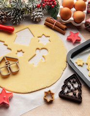 Baker is preparing christmas cookies using dough cutters and baking tray