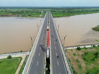Aerial photograph showing a highway bridge spanning a wide river, surrounded by lush green...
