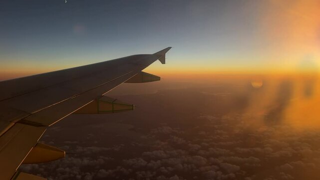 Aerial view of sunrise through airliner window in the morning. Aerial view of Cloudscape in dawn through plane window.