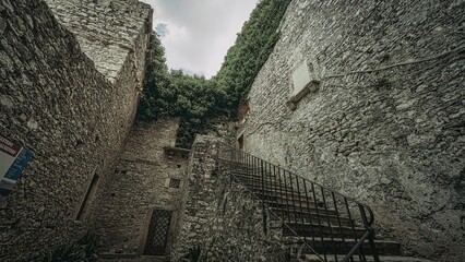 Historic stone stairway leading to a lush ivy-covered wall in Erice, Sicily, Italy