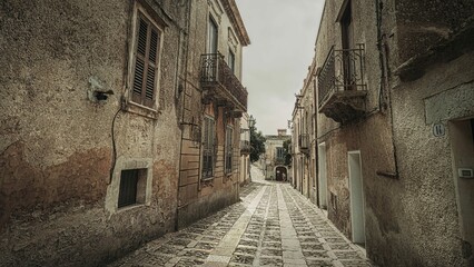 Charming narrow street in Erice, Sicily, Italy with rustic buildings and cobblestone path
