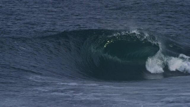slow motion wave rolls and crashes into a clean barrel, Atlantic storm clouds overhead