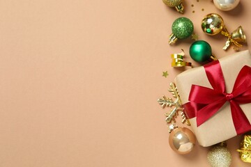 Beautiful gift box tied with bow and Christmas decorations on color background 