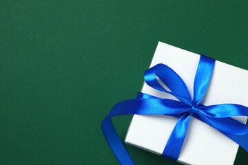 Beautiful gift box tied with bow on color background 