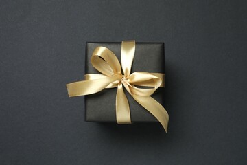 Beautiful gift box tied with bow on black background 