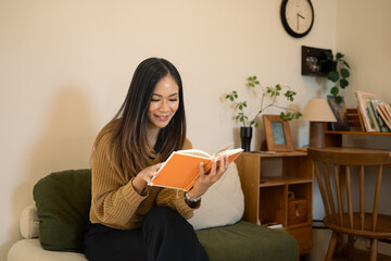 Pretty young woman relaxing in her living room and reading book