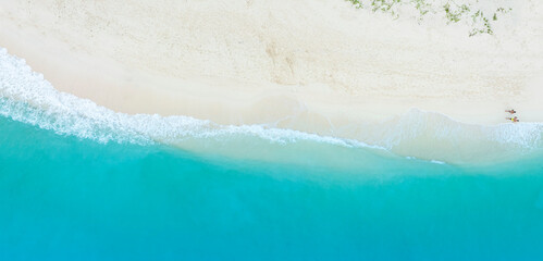 Tropical Beach with the soft wave water of the sea on the sandy beach background as texture with splashes and bubbles
