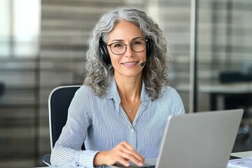 Happy middle aged woman customer service representative with headset smiling at desk in modern office