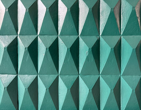 3D carved pyramidal and triangular 3D tiles in green tosca paint finish. 3D pyramid tiles for wall panel finishes, seamless background texture. 