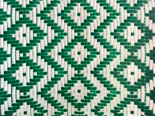 Closeup of synthetic green and white rattan or wicker weaving in chevron and diamond pattern....