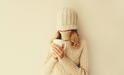 Happy funny young woman with cup of coffee drink in winter hat, sweater having fun on background