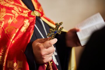 The hands of a priest with a cross and a bible. The Armenian Apostolic Church.